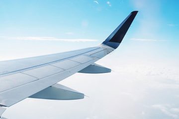 Aile d'un avion, qui survole les nuages d'un ciel bleu