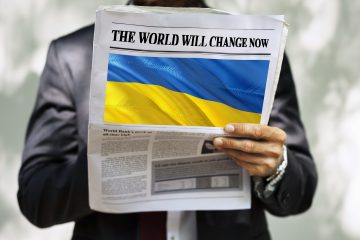 Un homme d'affaires en costume tien un magasine, sur la couverture, on peut voir un drapeau ukrainien ainsi que l'intitulé "the world will change now"